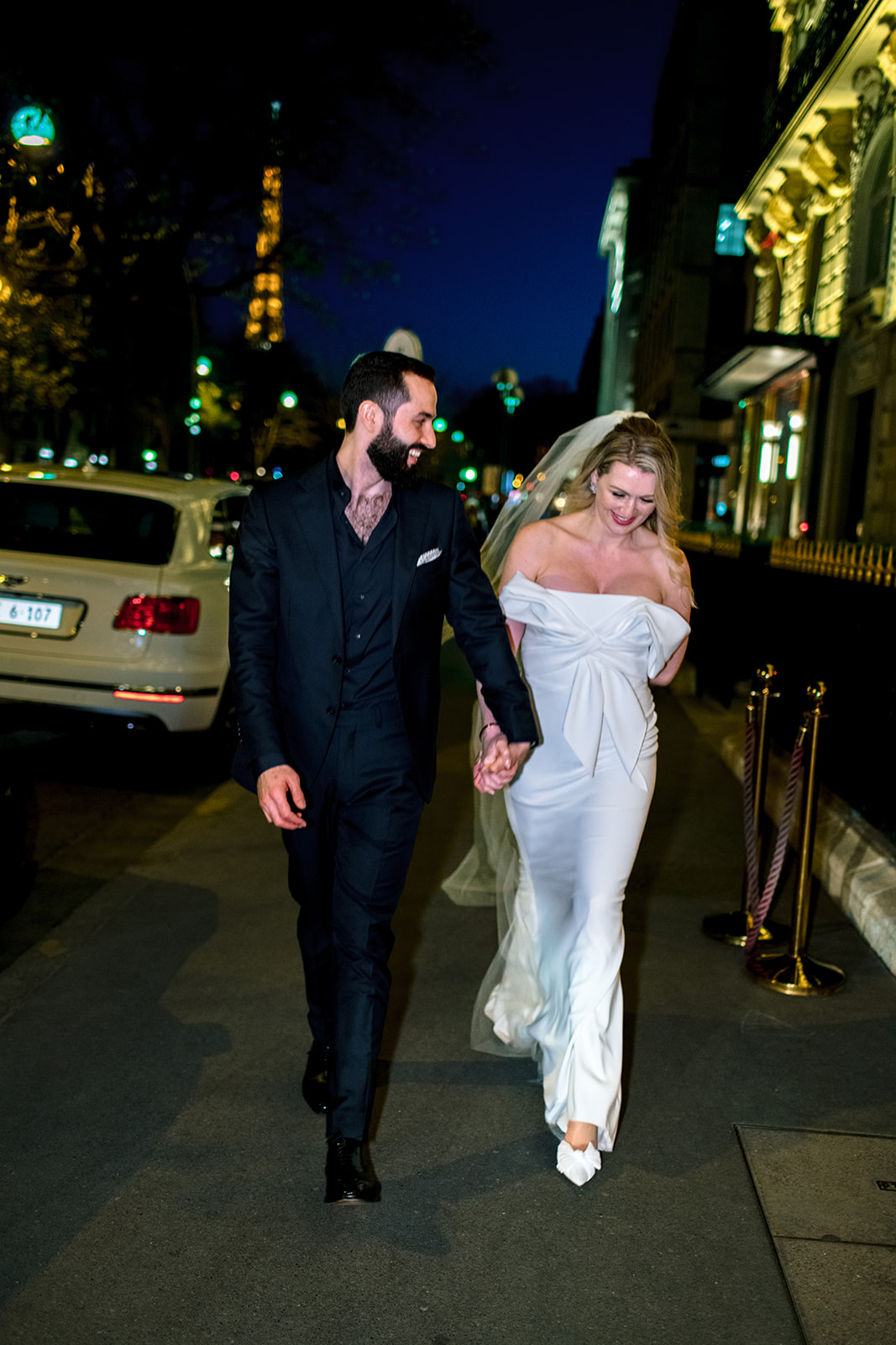 Bride and groom sharing a playful walk on Avenue Montaigne at night